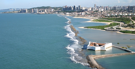 Vista área das praias urbanas com a Fortaleza dos Reis Magos e a praia do Forte (em forma de coração) em primeiro plano.