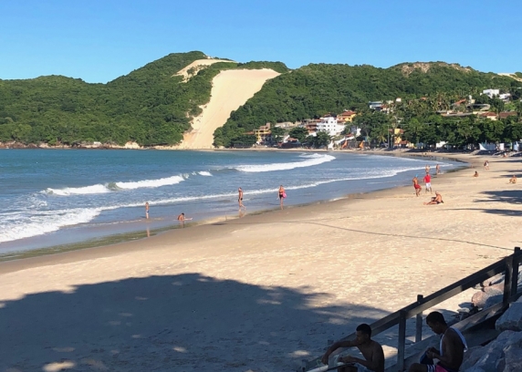 Poucos turistas ainda circulam na areia da praia de Ponta Negra.