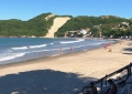 Poucos turistas ainda circulam na areia da praia de Ponta Negra.