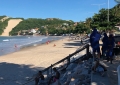 Pessoal da empresa de limpeza urbana observam os poucos turistas ainda na praia de Ponta Negra.