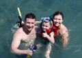 O casal Igor e Daniele com o filho Cauã mergulhando nas piscinas Naturais de Pirangi, no passeio de barco da Marina Badauê 
